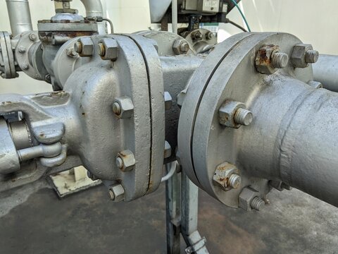 ​Close-up of industrial steel pipe valves and bolted flanges in factory system