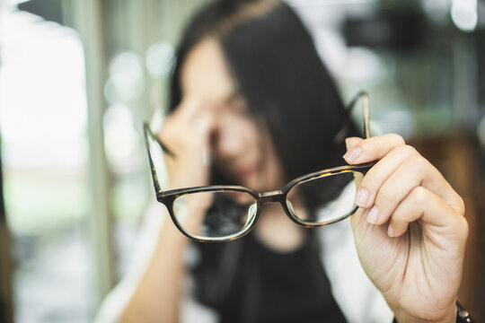 Woman experiencing blurred vision and eye strain while working on a laptop, illustrating tired eyes, visual fatigue, screen-related discomfort and digital eye health.
