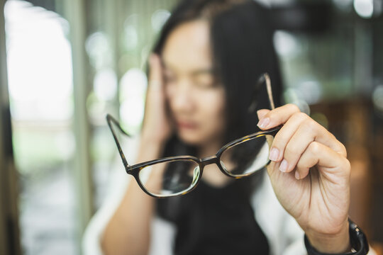 Woman experiencing blurred vision and eye strain while working on a laptop, illustrating tired eyes, visual fatigue, screen-related discomfort and digital eye health.