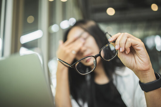 Woman experiencing blurred vision and eye strain while working on a laptop, illustrating tired eyes, visual fatigue, screen-related discomfort and digital eye health.