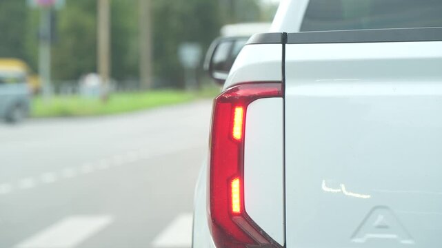 Delivery and utility trucks are a constant undercurrent of city traffic, a white pickup idling near a pedestrian crossing with its taillight glowing in close-up.