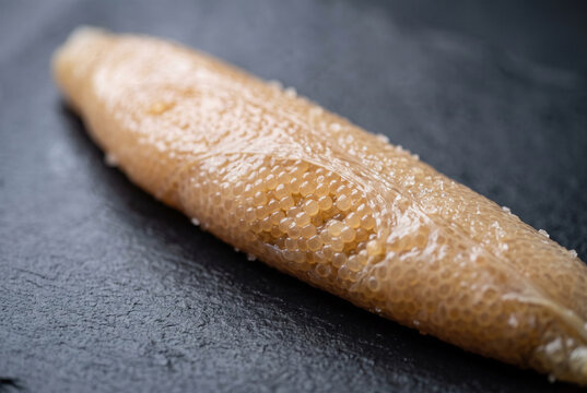 Raw Fish Roe Sac Filled With Eggs on Dark Stone Surface