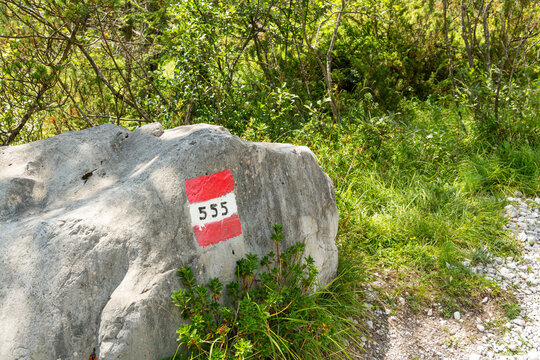 Taibon Agordino, Italy. Red and white hiking trail marker 555 on a rock in the Dolomites