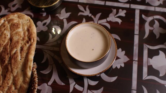 Delicious creamy soup and fresh bread on a decorated table, representing Middle Eastern cuisine
