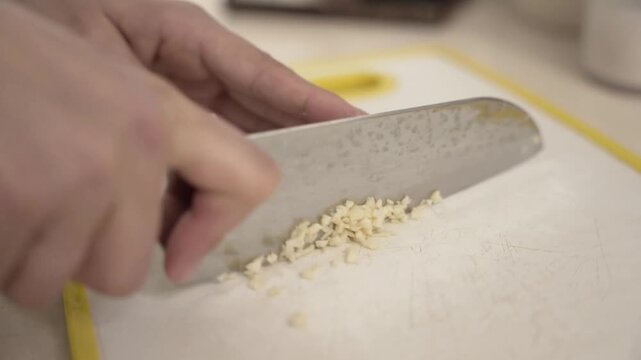 Caucasian hands chopping fresh garlic, raw food, cooking