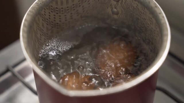 Close-up of brown shell eggs boiling. Hot water with bubbles, high-protein food