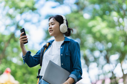 Student listening music using headphones and smartphone outdoors
