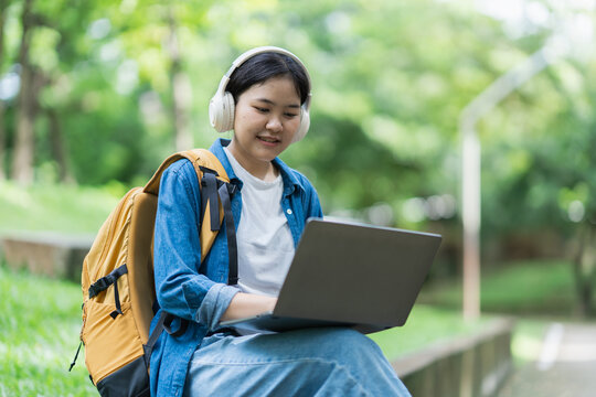 Student learning online using laptop and headphones outdoors
