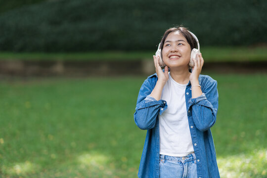 Asian girl listening to music enjoying happiness in park
