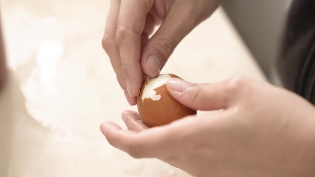 Woman hands starting to peel a brown boiled egg. Food preparation