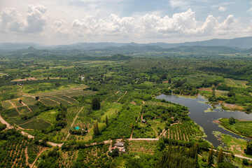 Obraz premium Aerial landscape countryside shot of Kaeng Krachan, Thailand, from above includes local communities, agricultural fields, and a mountain range, shot from a helicopter
