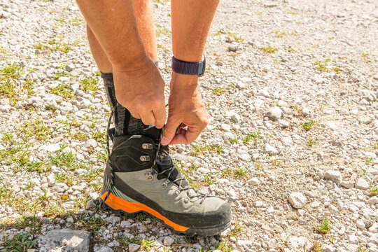 Taibon Agordino, Italy. Hiker fastening technical footwear on a rocky mountain trail during an alpine hike