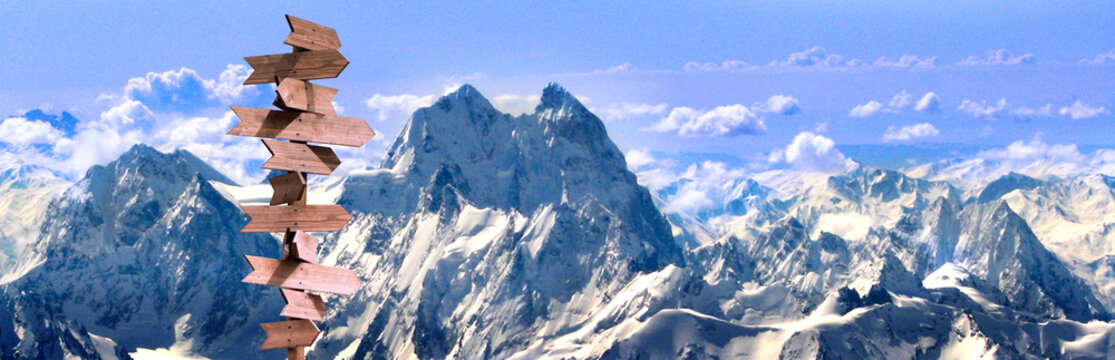 Snow-covered mountains and directional sign during daytime in a high-altitude area
