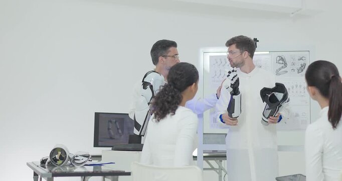 Engineers presenting and testing robotic arm at technical drawing board in white robotics lab