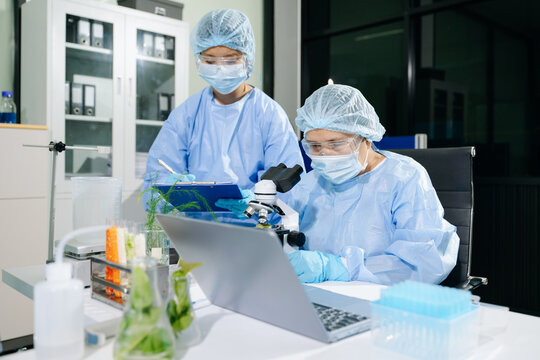 Two scientists in full PPE conduct food safety testing and organic plant biology research using advanced equipment
