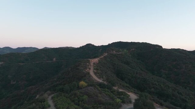 Aerial wide shot flying over the hiking trails at the Top of Reseda during sunset in Los Angeles, California. 4K