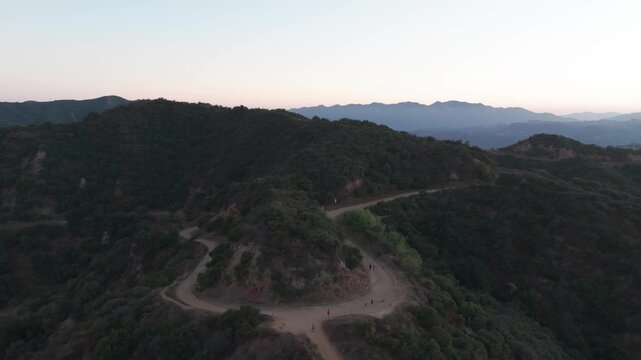 Wide panning aerial shot of the Top of Reseda hiking trails above Tarzana during sunset in Los Angeles, California. 4K
