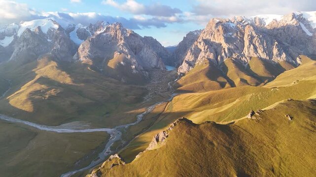 An aerial view of the typical landscape in the Kok Kiya Valley in Kyrgyzstan. Green valleys with pastures for horses, sheep and cows, and the high mountains with the Tian Shan glaciers. Summer holiday