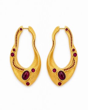 Sculptural rose gold and ruby hoop earrings in a flat lay arrangement