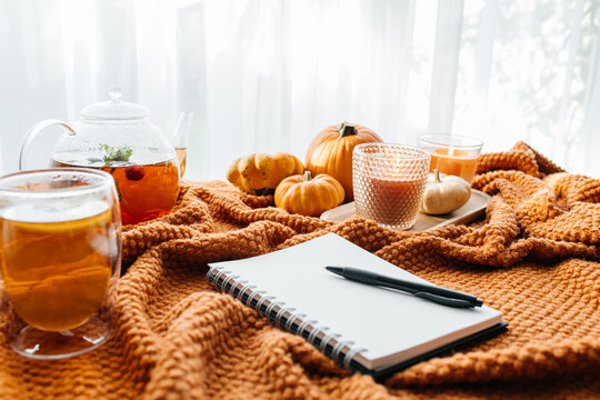 Autumn cozy mood with pumpkins, tea, and glowing candles