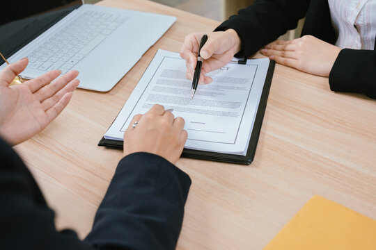 Business professionals reviewing and signing a contract document, representing legal agreements, corporate negotiations, business partnerships, and financial transactions.