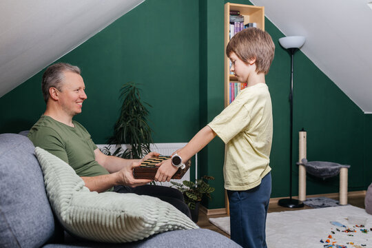 Father giving chess board game to son