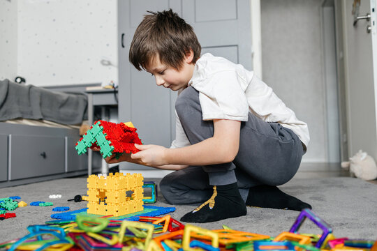Boy building house using colorful magnetic construction blocks