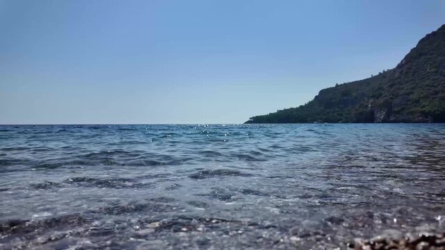 Slow motion sea waves on Cirali Beach, Turkey, with clear Mediterranean water and scenic coastal mountains