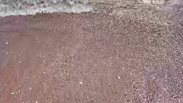 Sea waves washing over a pebble beach and wet stones in slow motion