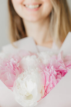 Young woman smiling receiving pink peony bouquet