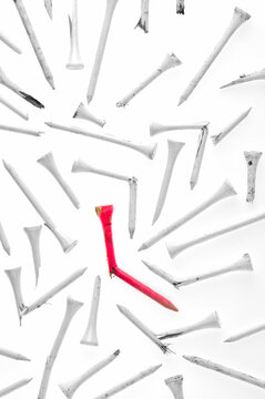 Broken red golf tee stands out among white ones