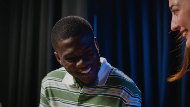 Young adult African American man rehearsing script lines with female peer during theater acting workshop. Commercial video suitable for performing arts, drama education and university campaigns