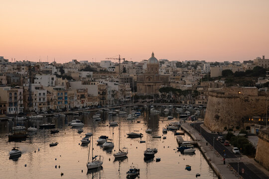 Historic Maltese harbor filled with boats at sunset
