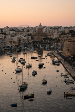 Boats moored in a historic Malta harbor at sunset
