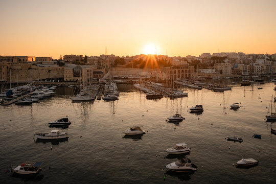 Golden sunrise over a historic Malta harbor