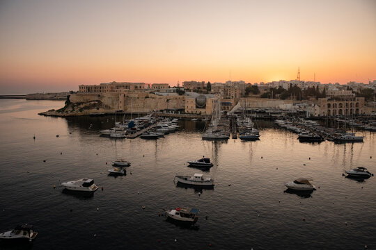 Boats moored in a calm Malta harbor at sunrise