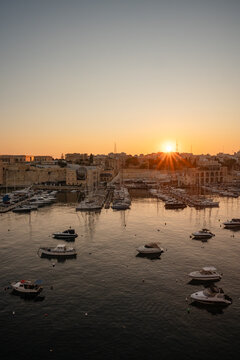 Golden sun rising over a tranquil Malta boat harbor