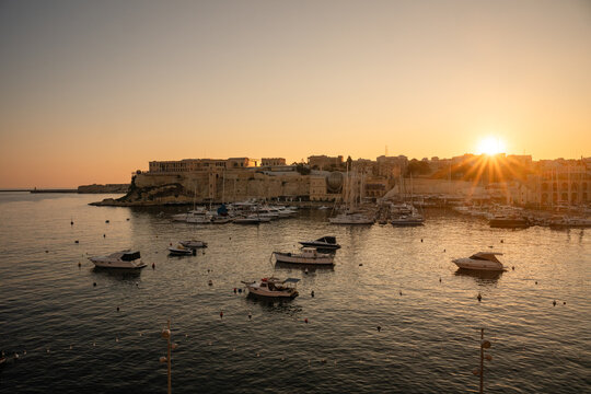 Boats in a historic Malta harbor at sunset