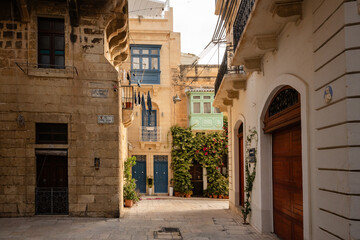 Obraz na płótnie Canvas Sunlit cobblestone street with colourful Maltese balconies
