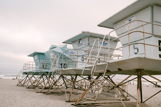 A row of light blue lifeguard towers on a sandy beach