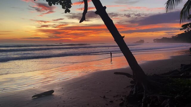 Fiery orange sunset reflects on a wet sandy beach