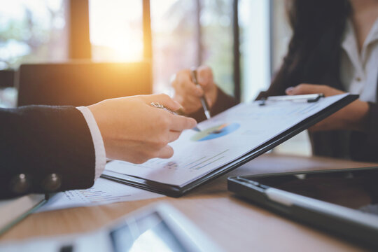 Business professionals reviewing financial charts and discussing investment strategies during a corporate meeting at a modern office.