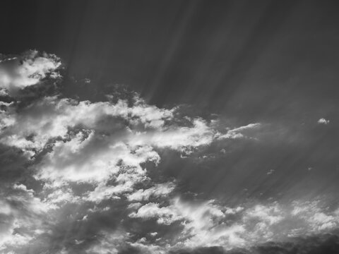 Monochrome sky with sun rays beaming through dramatic clouds