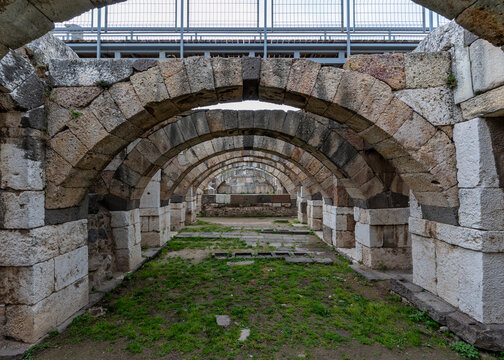 Ancient Roman stone arches and vaulted structures at the Smyrna Agora archaeological site in Izmir, Turkey, with modern protective barriers visible overhead