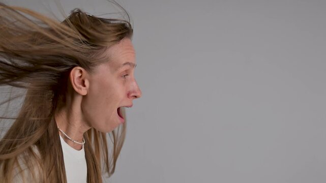 A portrait of a Caucasian woman with braces. A sudden gust of air flutters her hair.