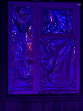 Purple glow illuminates window pane with reflective plastic