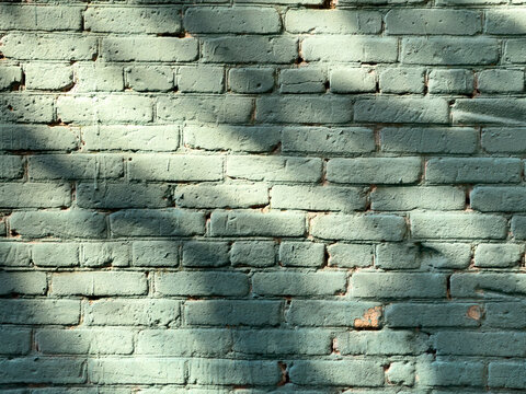 Green painted brick wall with shadow patterns