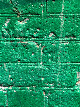 Vibrant green paint covers weathered brick wall