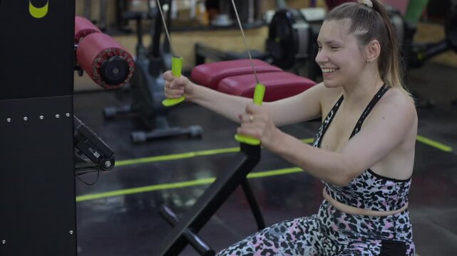 A Caucasian woman with cerebral palsy exercises with dumbbells in a gym.