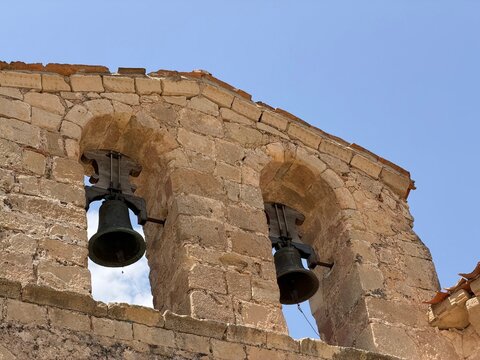 Old bells hanging in stone bell tower under clear sky